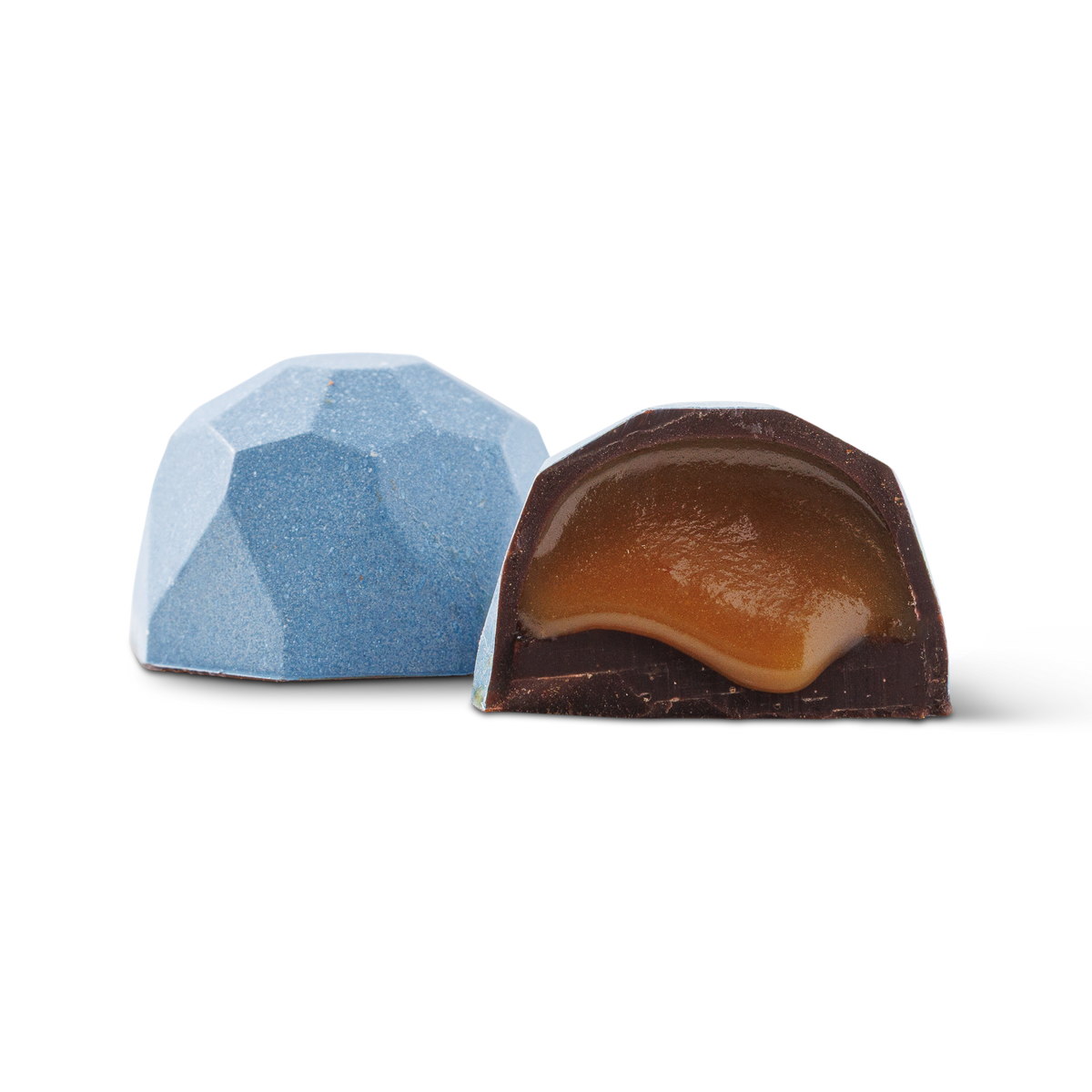 Two faceted gourmet chocolates on a white background, with one whole chocolate in light blue and one cut open showing a caramel-colored filling.